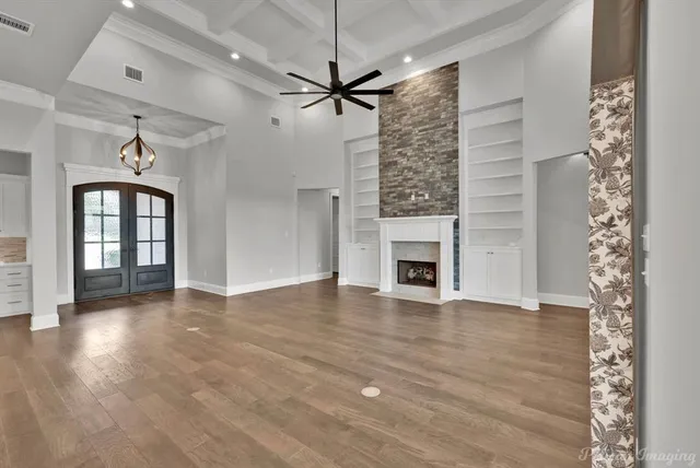 a view of a livingroom with a fireplace a ceiling fan and windows