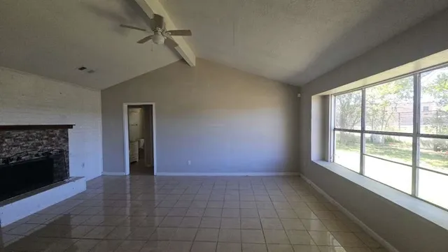 a view of an empty room with a fireplace and a window