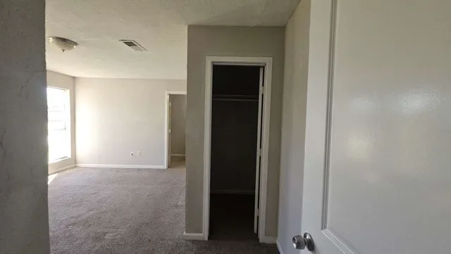 a view of an empty room with closet and a window