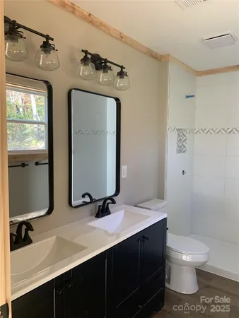 a bathroom with a double vanity sink toilet mirror and shower