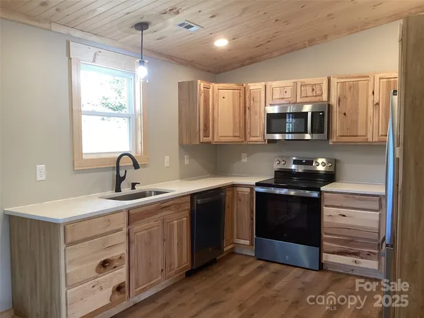 a kitchen with stainless steel appliances granite countertop a stove a sink dishwasher a microwave oven and a refrigerator with wooden floor