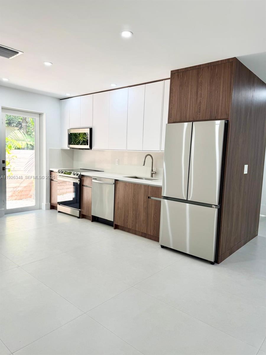 524 Northeast 65th Street, Unit 2 Miami, FL 33138 - Photo 6 of 24 a kitchen with stainless steel appliances a refrigerator a sink a stove a microwave a center island and chairs