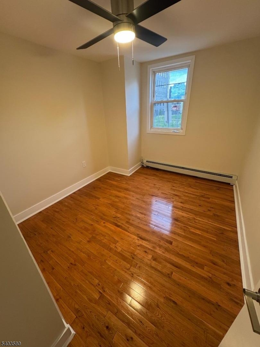 93 Bruen Street Newark, NJ 07105 - Photo 6 of 9 an empty room with wooden floor and windows