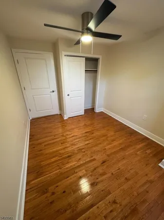 an empty room with wooden floor and fan