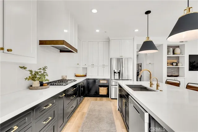 a kitchen with kitchen island stainless steel appliances a sink a counter top space stove refrigerator and cabinets