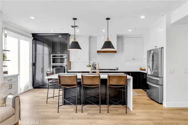 a kitchen with stainless steel appliances kitchen island granite countertop a table chairs stove and refrigerator