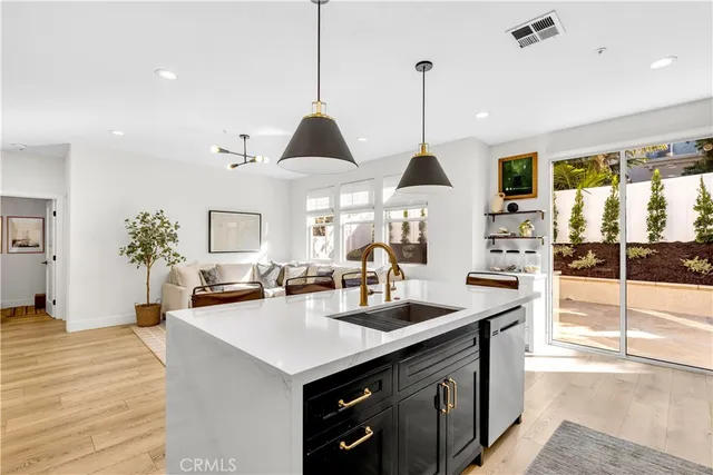 a kitchen with stainless steel appliances granite countertop a sink a stove and a wooden floor