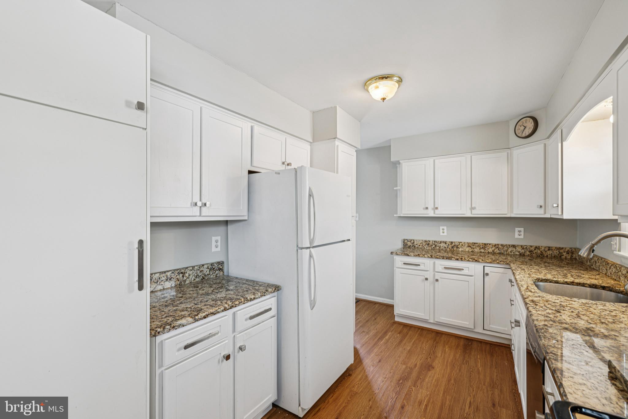 917 Century Street Hampstead, MD 21074 - Photo 12 of 45 a kitchen with granite countertop a refrigerator a stove a sink and white cabinets with wooden floor