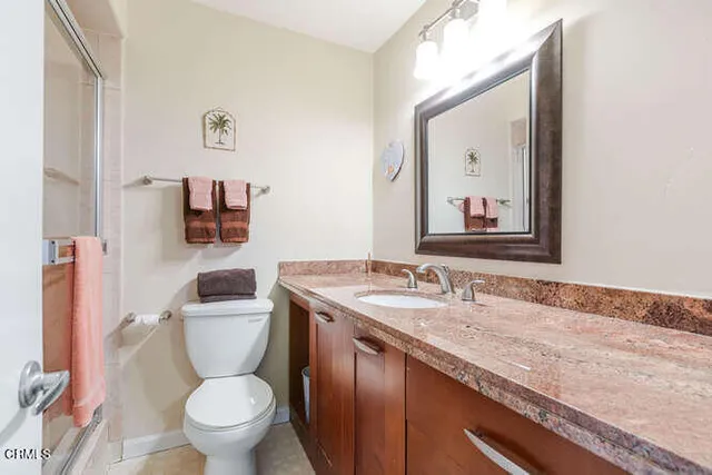 a bathroom with a granite countertop toilet sink and mirror