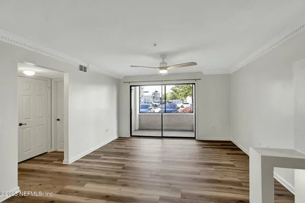 a view of empty room with wooden floor and fan