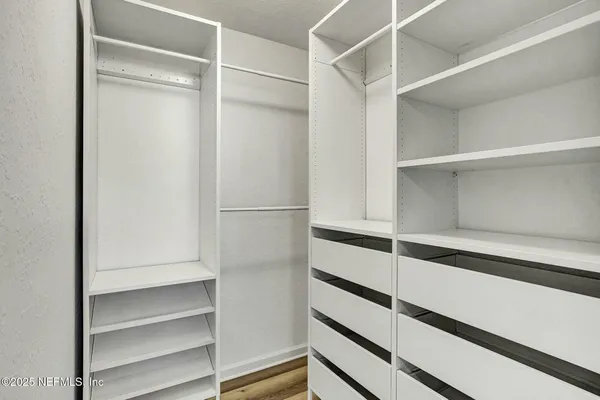 a view of walk in closet with empty racks