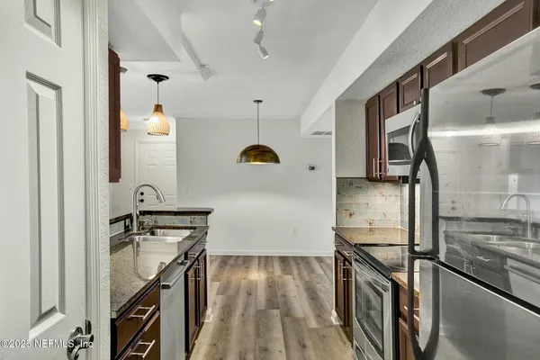 a kitchen with stainless steel appliances granite countertop a stove a sink and a refrigerator