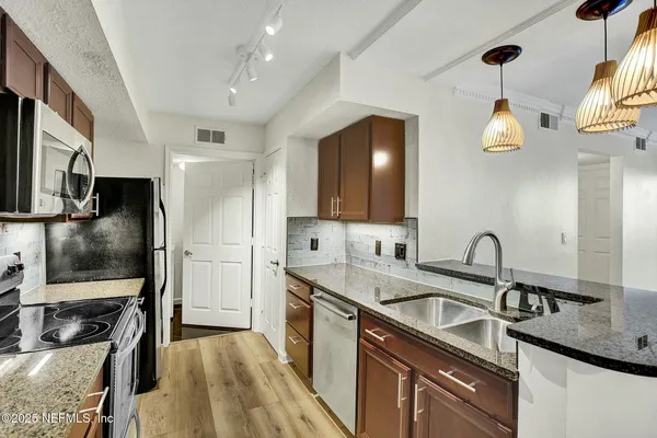 a kitchen with stainless steel appliances granite countertop a sink a stove and refrigerator