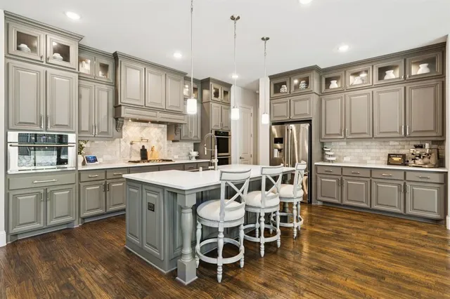 a kitchen with a dining table chairs wooden floor cabinets appliances and a window
