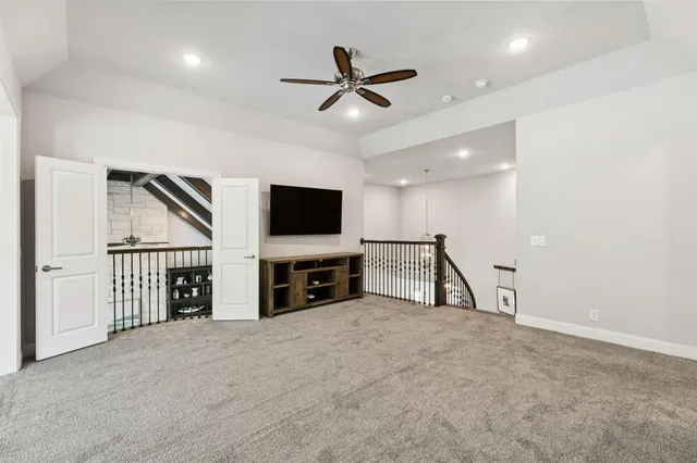 a view of an empty room with wooden floor and a ceiling fan