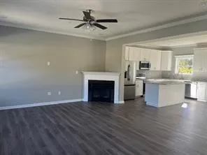 a view of a livingroom with a fireplace a ceiling fan and windows