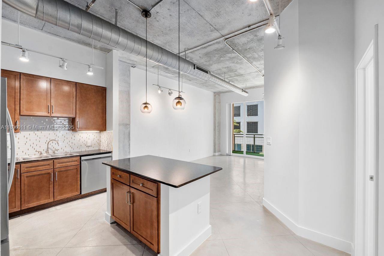 a kitchen with stainless steel appliances granite countertop a sink and dishwasher a refrigerator with wooden cabinets