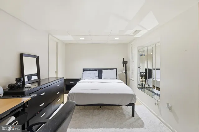 a bedroom with a bed and a large mirror on the dresser