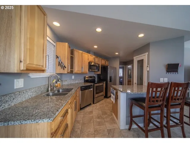 a kitchen with stainless steel appliances granite countertop table chairs sink and cabinets