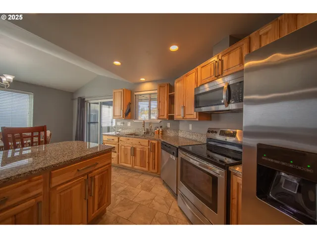 a kitchen with stainless steel appliances granite countertop a stove a sink and a microwave