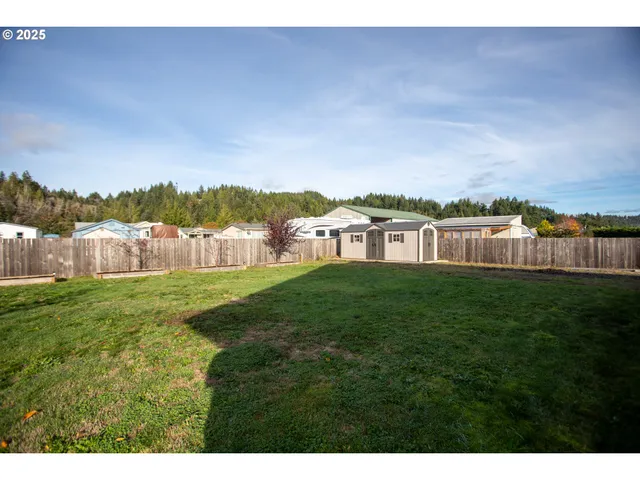 a view of a yard in front of a house with plants and wooden fence