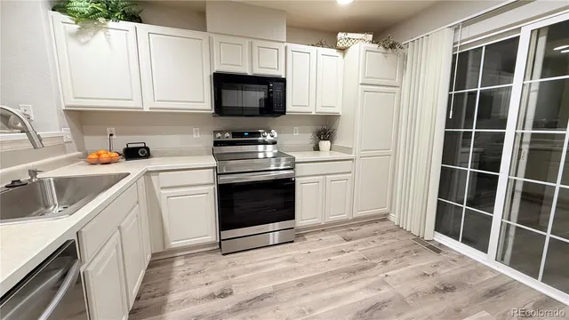 a kitchen with stainless steel appliances a stove a sink and white cabinets