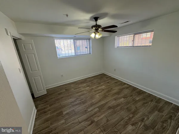 a view of empty room with wooden floor and fan