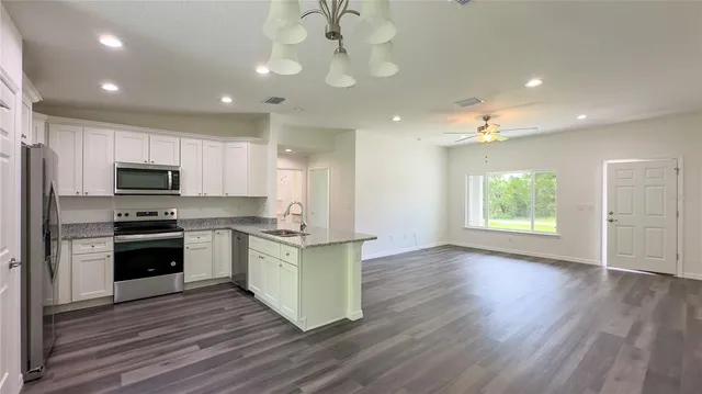 a kitchen with stainless steel appliances kitchen island granite countertop a stove a sink and a refrigerator