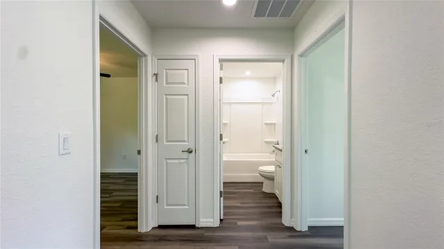 a view of empty room with wooden floor and fan