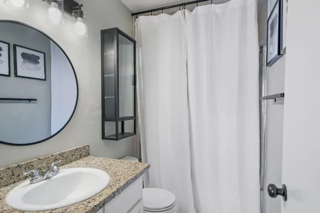 a bathroom with a granite countertop sink and a mirror