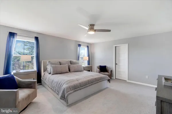 a bedroom with a large bed couch and windows