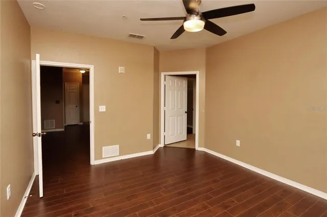 an empty room with wooden floor closet and a ceiling fan