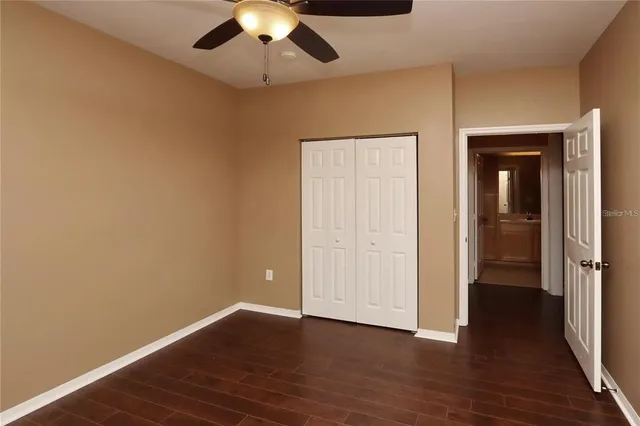 an empty room with wooden floor closet and windows