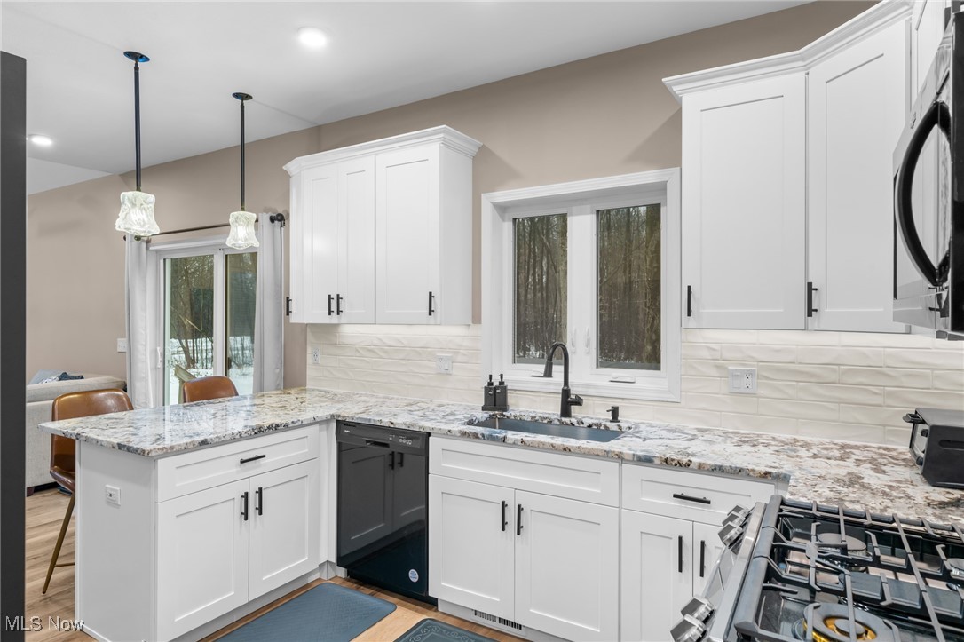 39600 Aurora Road Solon, OH 44139 - Photo 14 of 49 Kitchen featuring a peninsula, white cabinetry, a kitchen bar, light stone counters, and appliances with stainless steel finishes, sliders to a private bkyd
