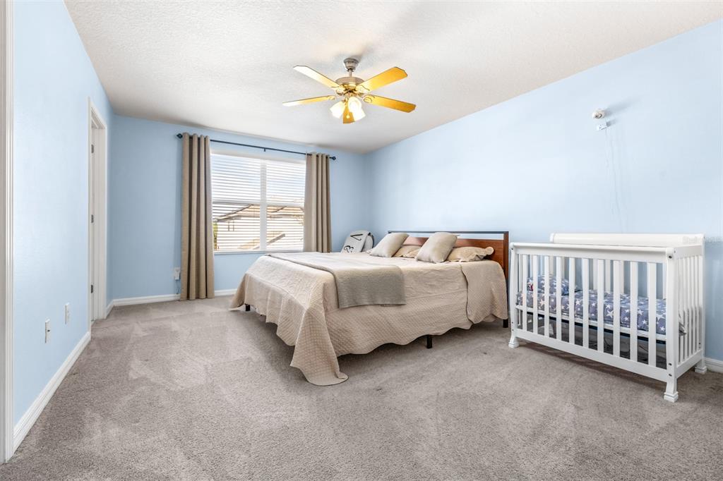 16713 Scenic Hill Way Wimauma, FL 33598 - Photo 24 of 52 a bedroom with a bed and a chandelier