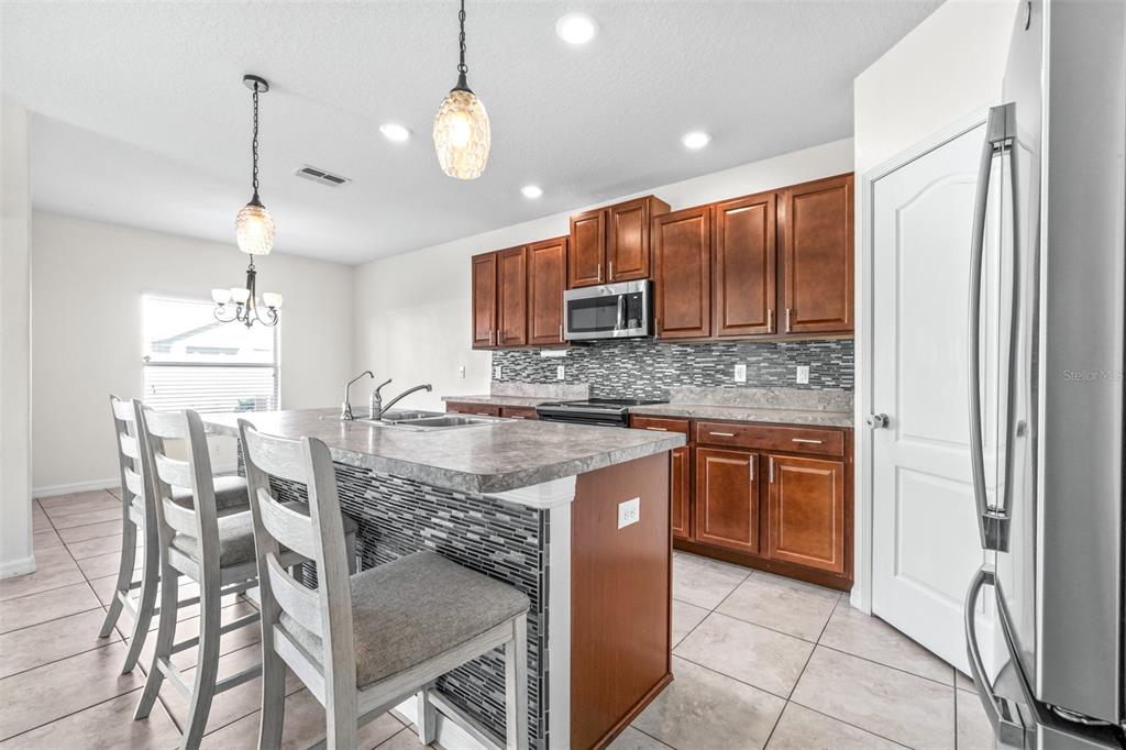 16713 Scenic Hill Way Wimauma, FL 33598 - Photo 10 of 52 a kitchen with kitchen island granite countertop wooden cabinets a counter top space and stainless steel appliances