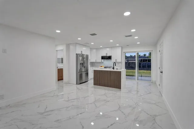 a large white kitchen with stainless steel appliances granite countertop a large counter top and a stove top oven