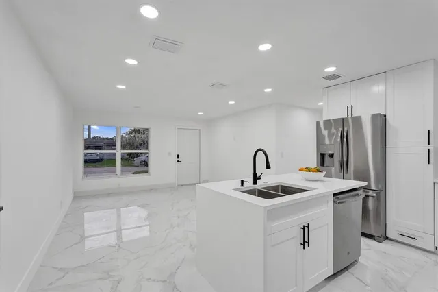 a kitchen with stainless steel appliances granite countertop a sink and a refrigerator