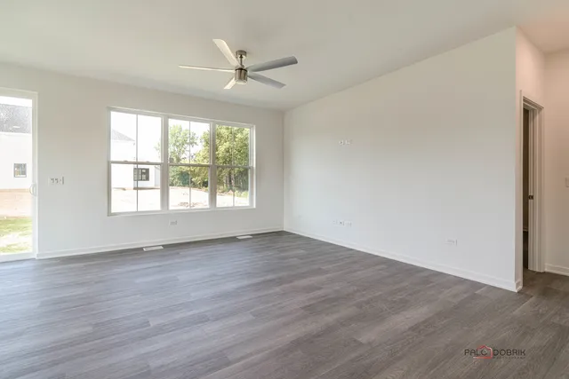 an empty room with wooden floor fan and windows