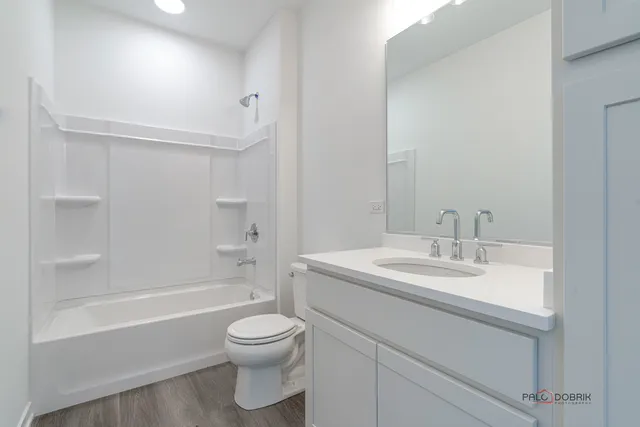 a bathroom with a bathtub shower sink vanity mirror and toilet