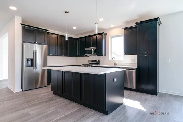 a kitchen with stainless steel appliances granite countertop a refrigerator a sink and a stove