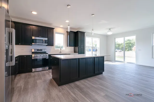 a kitchen with stainless steel appliances kitchen island granite countertop a stove a sink and a microwave