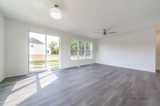 an empty room with wooden floor fan and windows