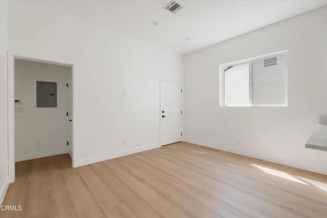 a view of an empty room with wooden floor and a window