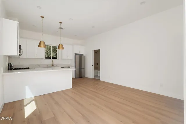 a view of a kitchen with a sink and dishwasher a refrigerator with wooden floor