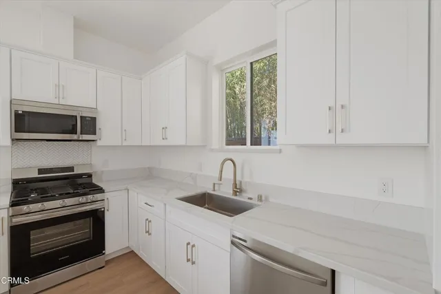 a kitchen with appliances a sink and cabinets