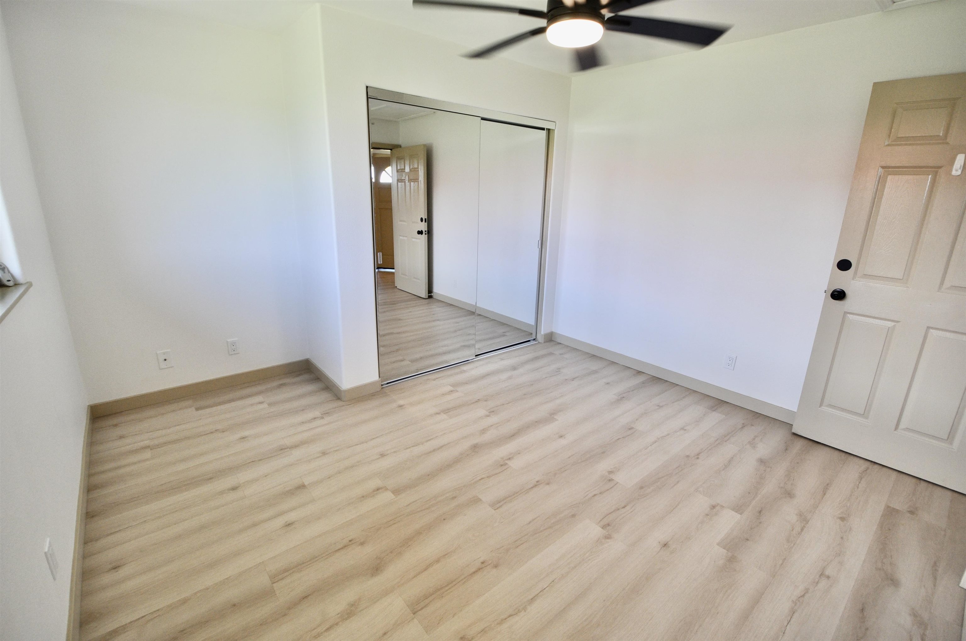 2835 Kaupakalua Road Haiku, HI 96708 - Photo 13 of 31 an empty room with wooden floor fan and windows