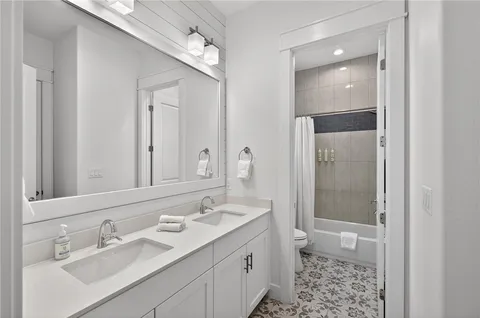 a bathroom with a double vanity sink toilet and shower