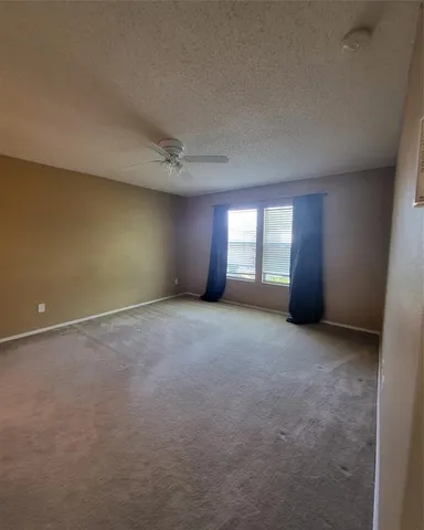 a view of an empty room with a ceiling fan and window