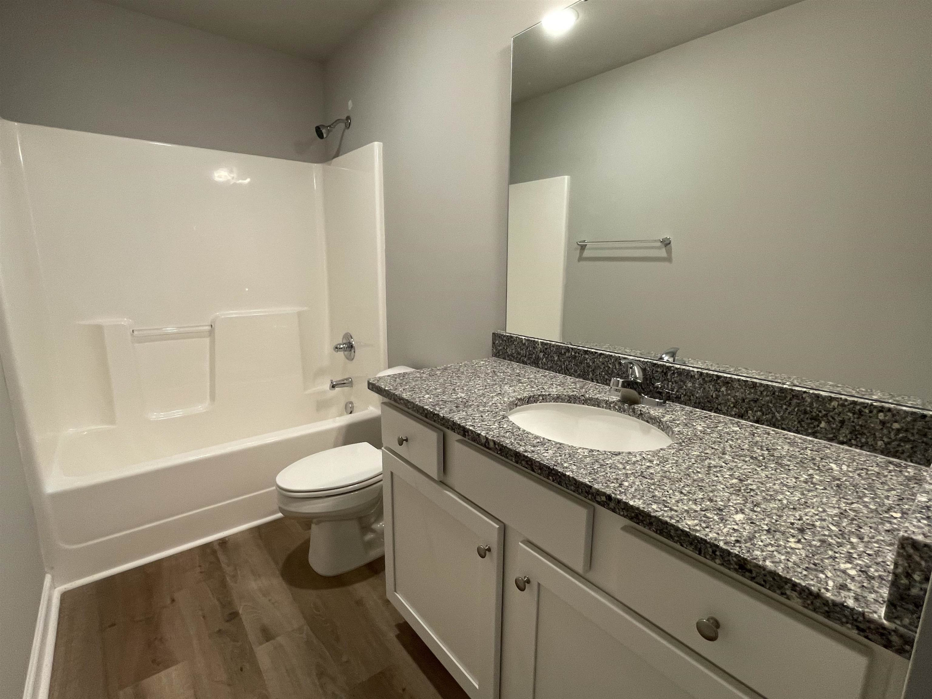 496 Roberts Road Willow Spring, NC 27592 - Photo 9 of 15 a bathroom with a granite countertop sink a toilet a mirror and bathtub
